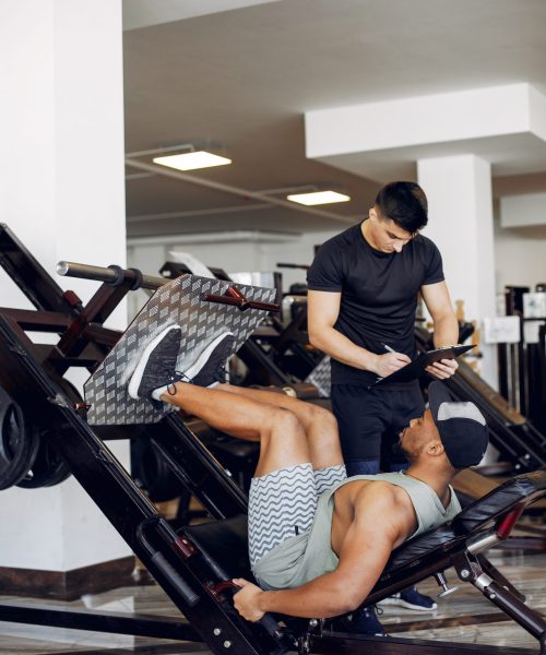 Sports men in the gym. A man performs exercises. Guy in a black t-shirt